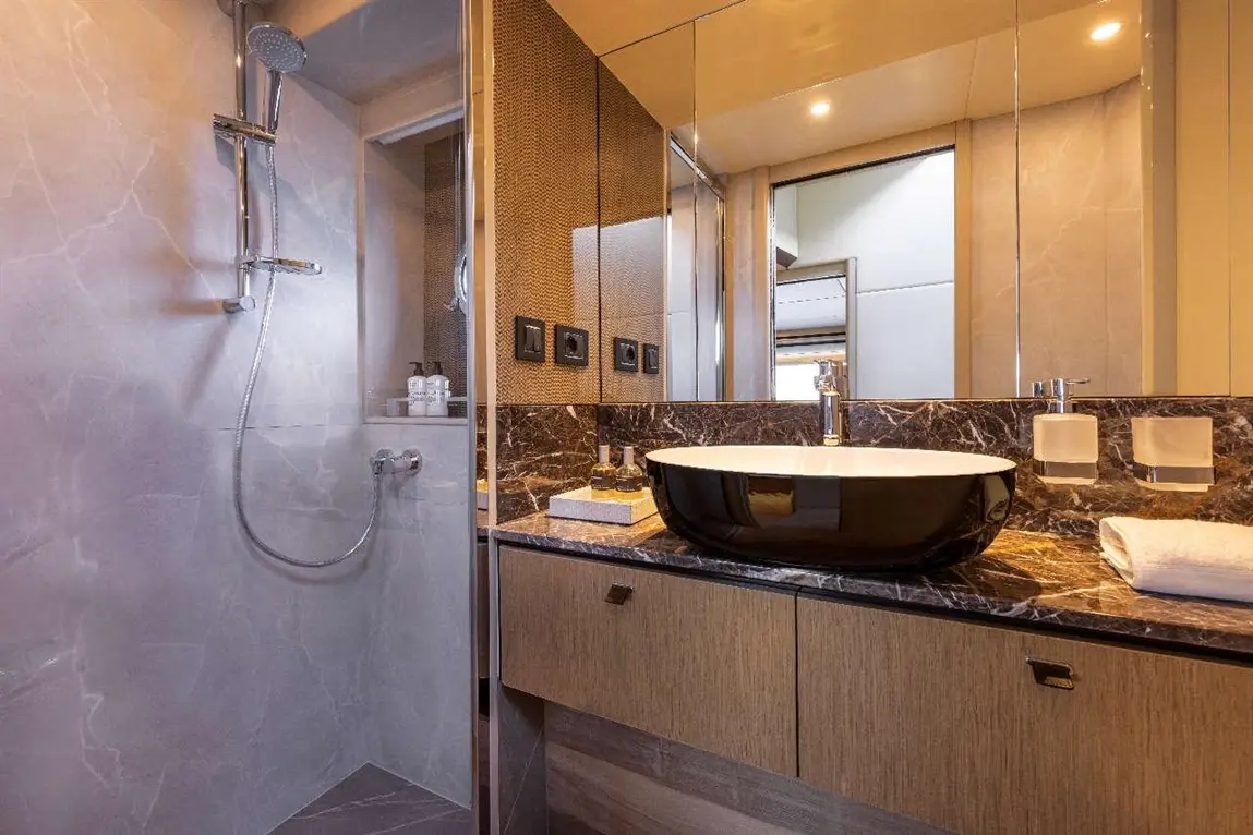 Stylish bathroom featuring a chrome shower, black vessel sink, marble countertop, and modern fixtures.